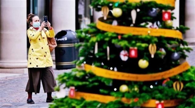 بريطانية تضع الكمامة وتلتقط صورة لشجرة عيد الميلاد 